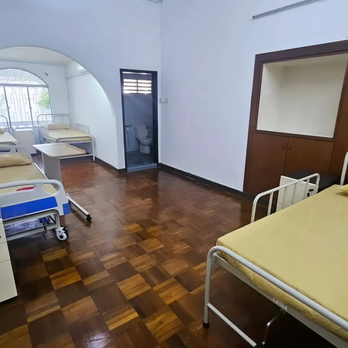 Resident room with hospital beds and en-suite bathroom at Prowell Elderly Home Care Centre