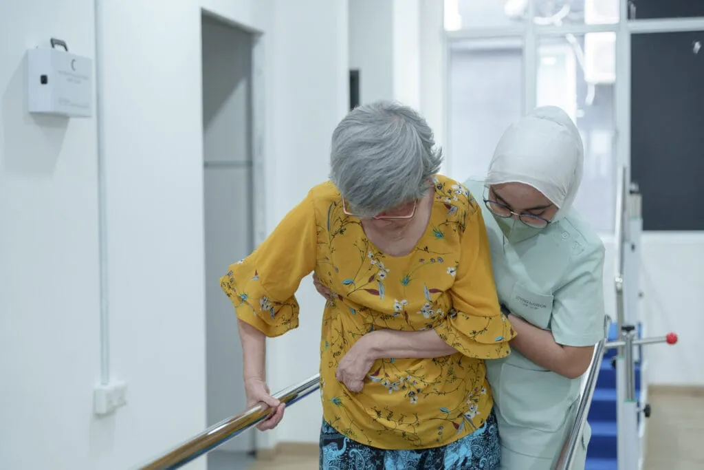 Nurse assisting resident with walking in the corridor at Loving Mansion