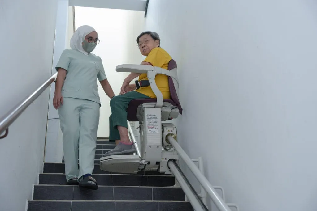 Resident using stair lift assisted by a nurse at Loving Mansion Care Centre